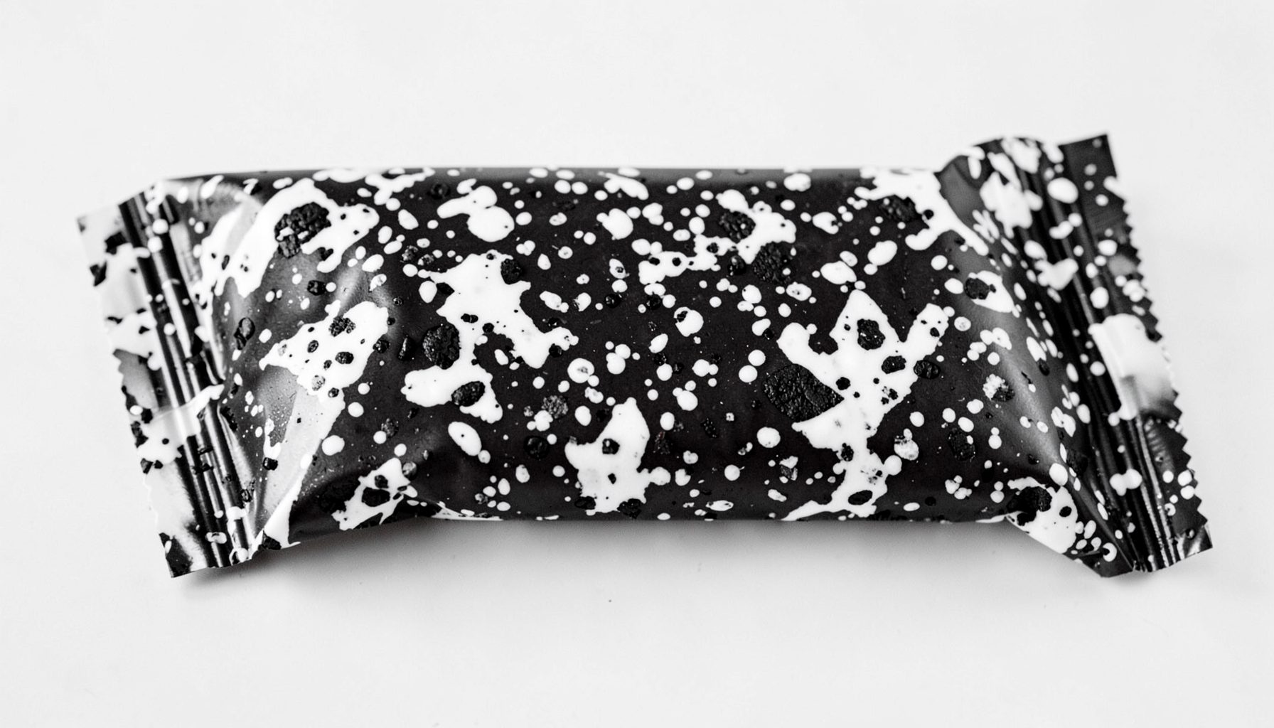 Chocolate bar packaging in black and white speckled tones resembling cookies and cream, playful mood